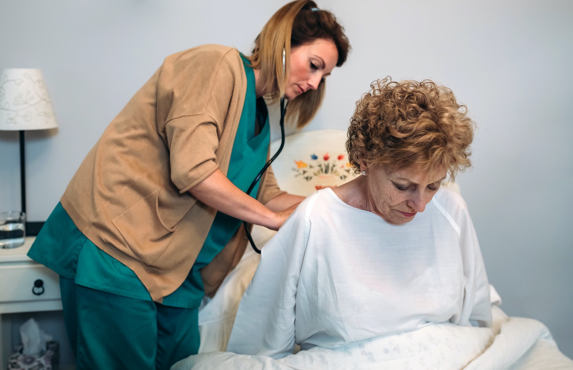 Caregiver auscultating senior woman