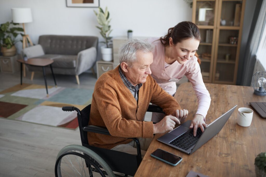 Caregiver Helping Senior Man Using Laptop