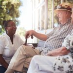 Senior couple with caregiver sitting outside